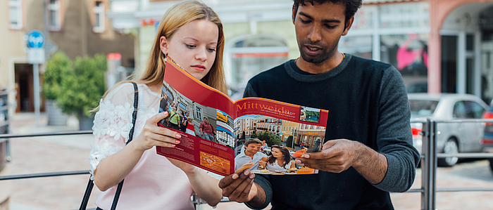 Two international students look at a magazine