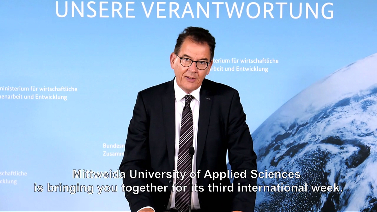 : Screenshot of the video message by Dr Gerd Müller, Federal Minister for Economic Cooperation and Development. The subtitle reads: "Mittweida University is bringing you together for its third international week".